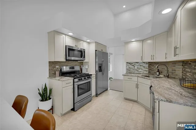 a kitchen with stainless steel appliances granite countertop a stove refrigerator sink and microwave