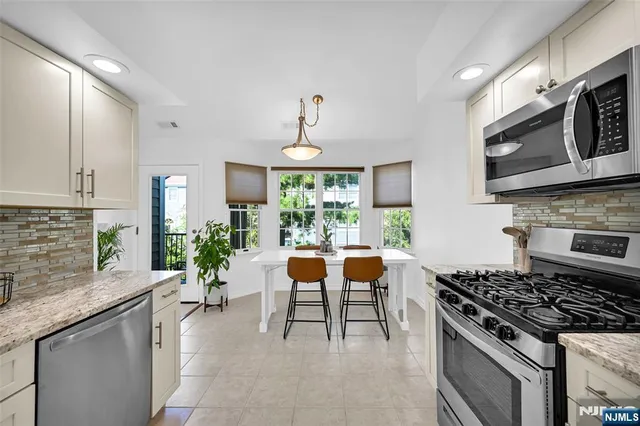 a kitchen with stainless steel appliances granite countertop a stove top oven a sink a dining table and chairs