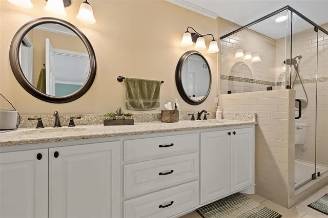 a bathroom with a granite countertop double vanity sink and a mirror