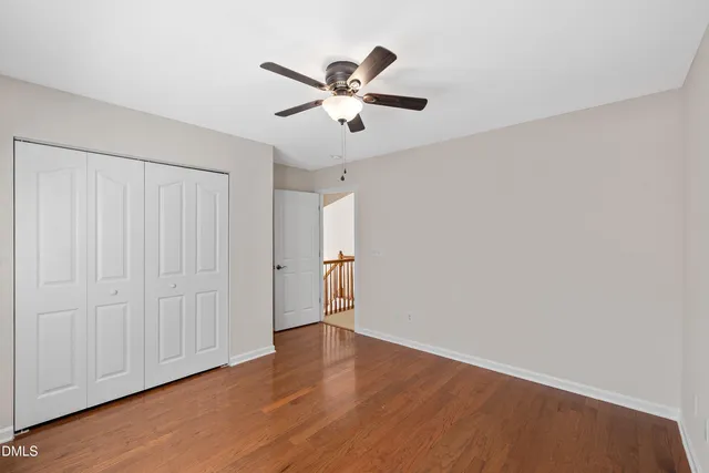 a view of an empty room with chandelier fan and a window