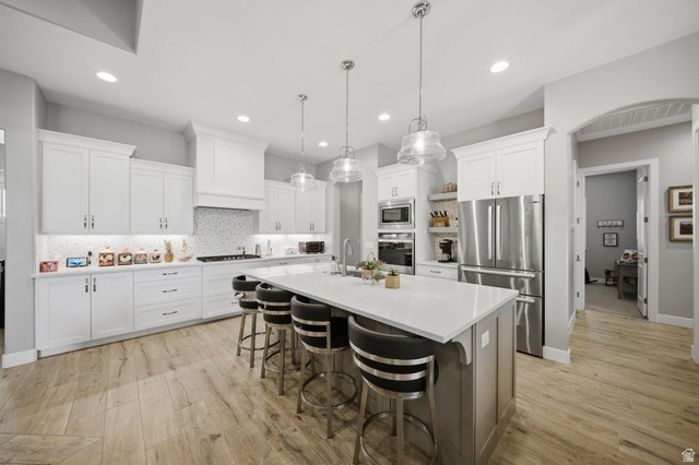 2829 East 1880th Street South St. George, UT 84790 - Photo 13 of 54 Two tone kitchen featuring stainless steel appliances, a center island with sink, a breakfast bar, tasteful backsplash, and pendant lighting