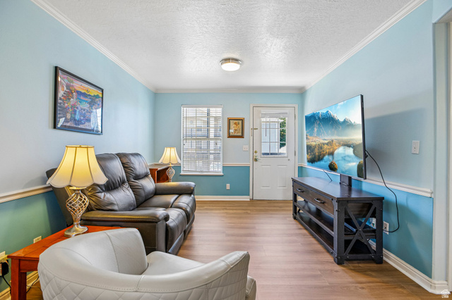 888 600 West, Unit 40 Provo, UT 84604 - Photo 6 of 19 Living area featuring wood-finish flooring, light blue wall paint, white crown molding, and a white entry door with frosted glass panes
