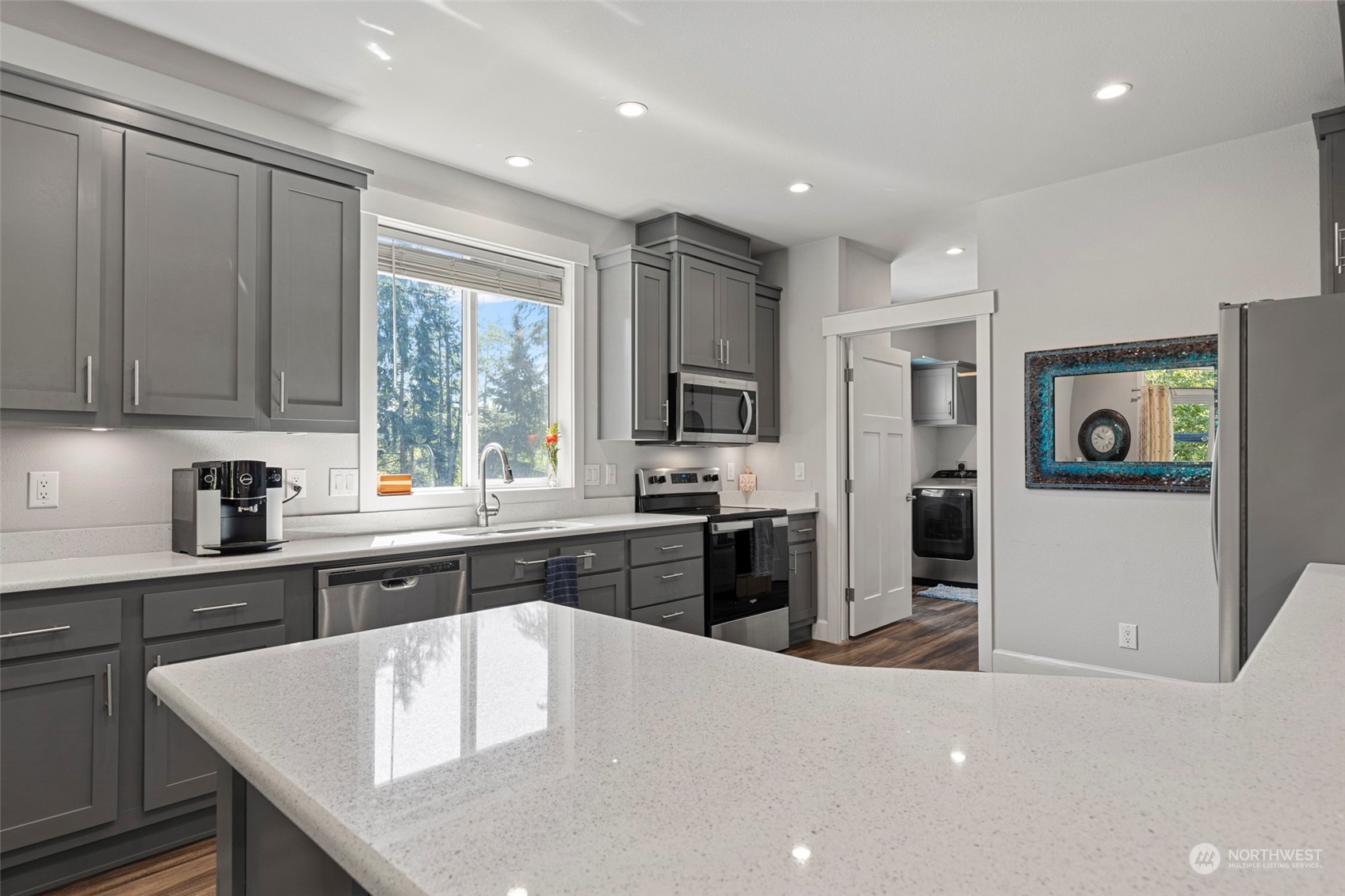 6303 Kirkhill Road Clinton, WA 98236 - Photo 15 of 40 a large kitchen with stainless steel appliances granite countertop a refrigerator a sink dishwasher a stove and white countertops with wooden floor