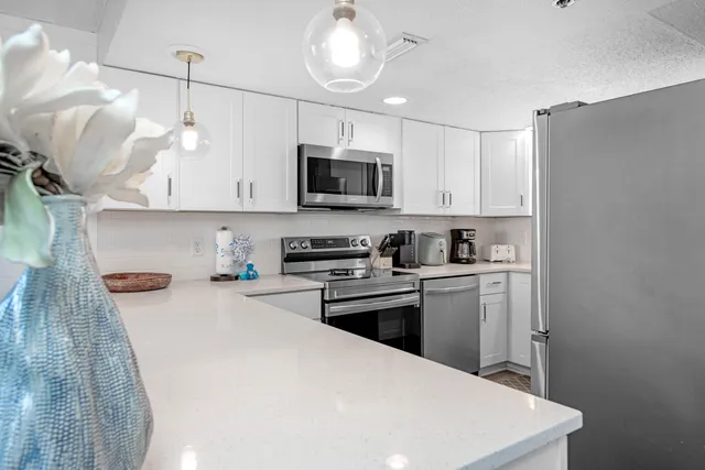 a kitchen with kitchen island white cabinets and stainless steel appliances