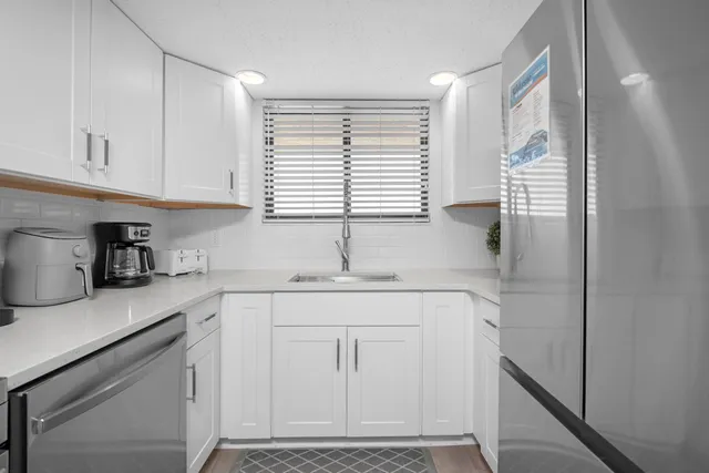 a kitchen with white cabinets and window