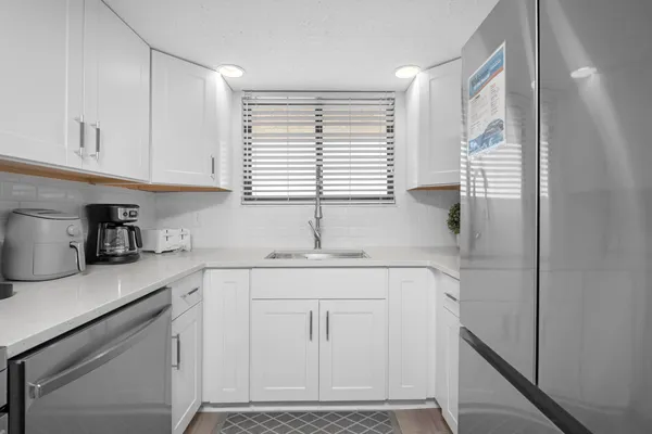 a kitchen with white cabinets and window