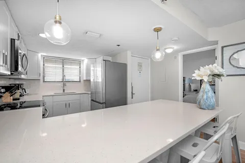 a large white kitchen with a stove a sink a refrigerator and chandelier