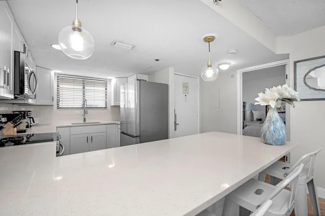 a large white kitchen with a stove a sink a refrigerator and chandelier