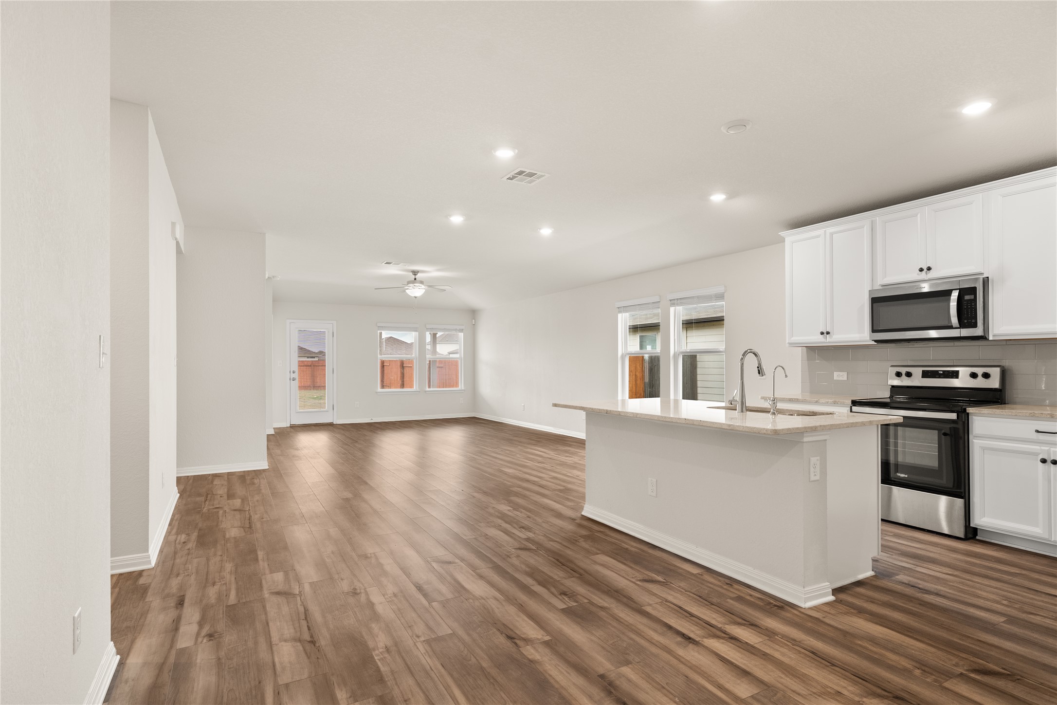 105 Saviano Road Hutto, TX 78634 - Photo 5 of 22 A well-lit open-concept space showcasing a modern kitchen island and rich wood flooring.