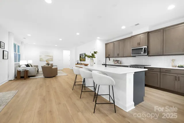 a kitchen with stainless steel appliances granite countertop a stove top oven a sink dishwasher and a refrigerator with wooden floor