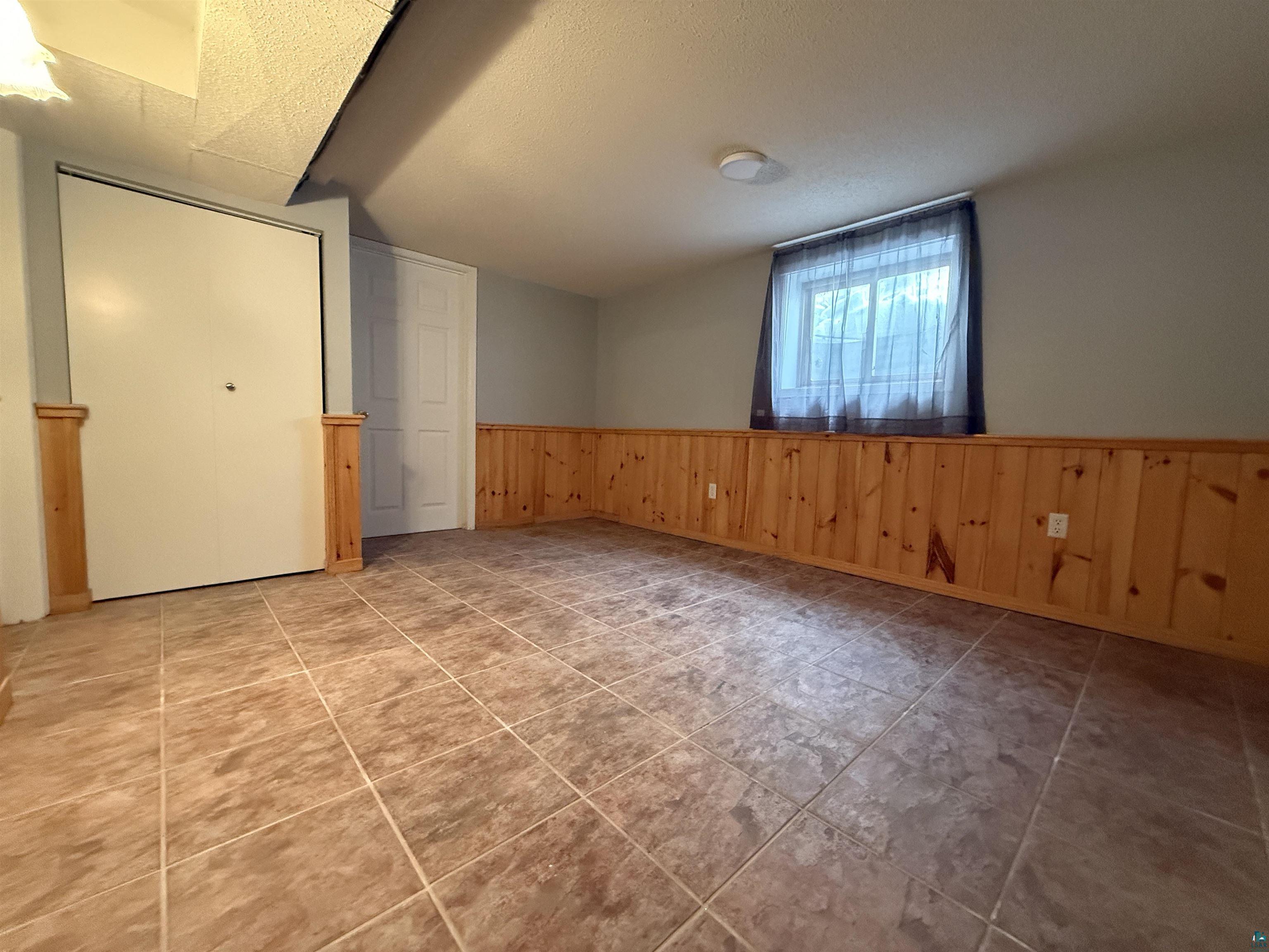 1321 South 13th Street Virginia, MN 55792 - Photo 22 of 33 Spare room with wainscoting, wooden walls, and a textured ceiling