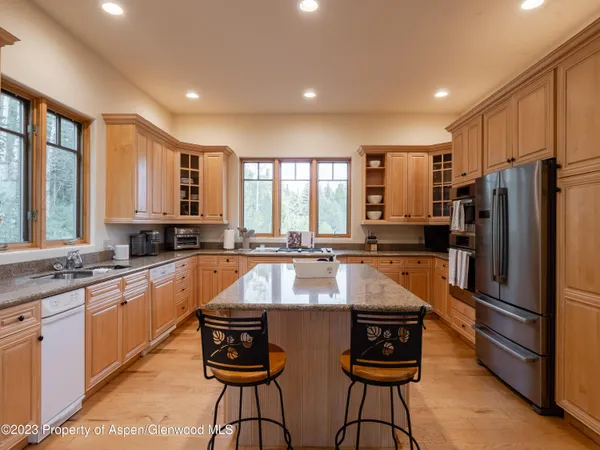 a large kitchen with granite countertop a stove a sink a refrigerator and a cabinets