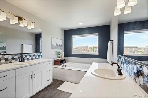a bathroom with double vanity sinks a large mirror and a bathtub