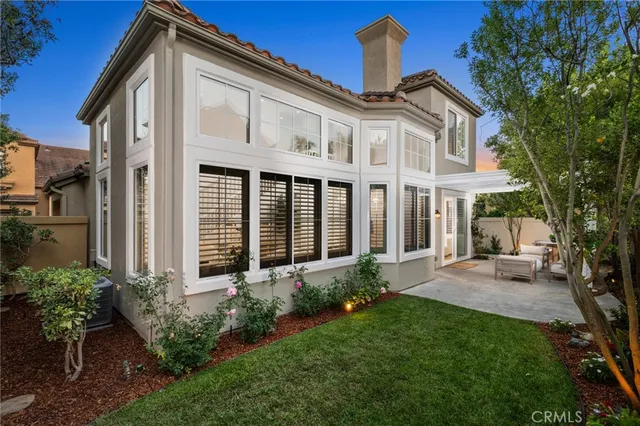 a view of a white house next to a yard with potted plants