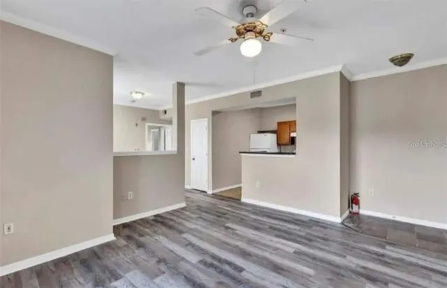 a view of empty room with wooden floor and ceiling fan
