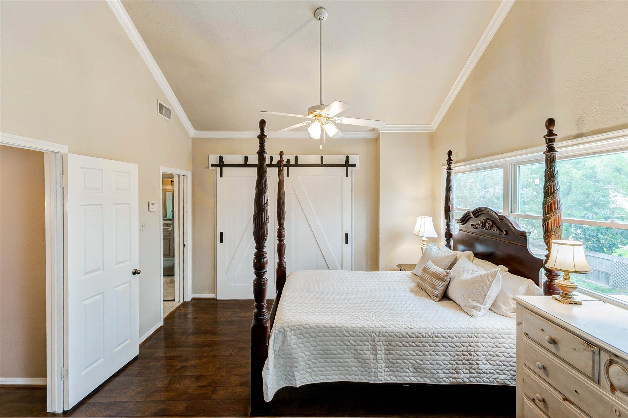 15811 Spring Forest Drive Houston, TX 77059 - Photo 19 of 27 Discover the inviting charm of this primary suite, featuring elegant wood laminate floors, abundant natural light, and stylish barn doors, creating a cozy yet sophisticated retreat.