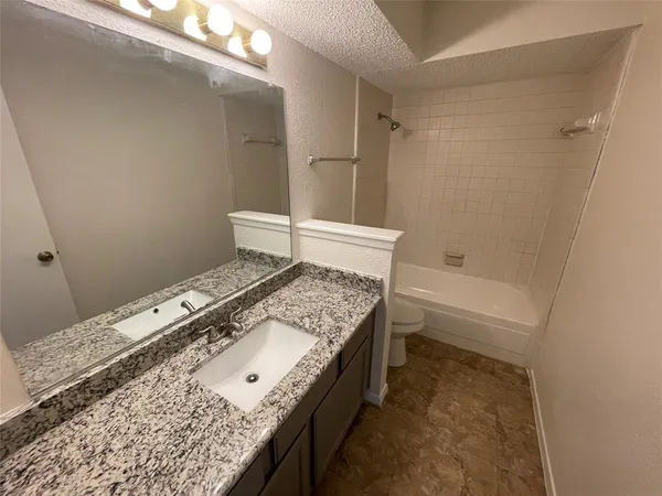 a bathroom with a granite countertop sink a toilet and shower