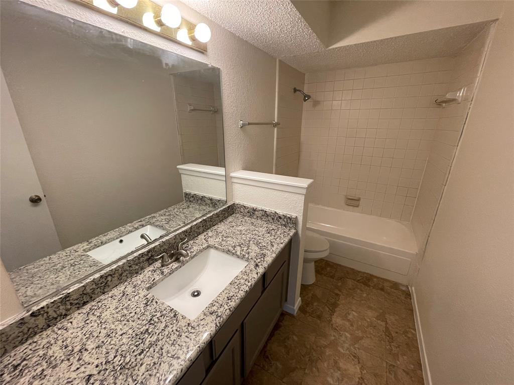 2510 Stanford Street, Unit A Rowlett, TX 75088 - Photo 8 of 11 a bathroom with a granite countertop sink a toilet and shower