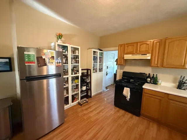 a kitchen with granite countertop a refrigerator and a stove top oven