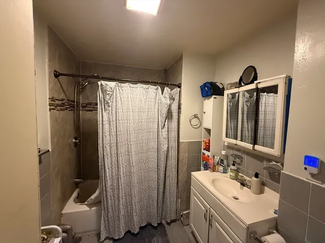 a bathroom with a sink vanity granite tub shower and a mirror