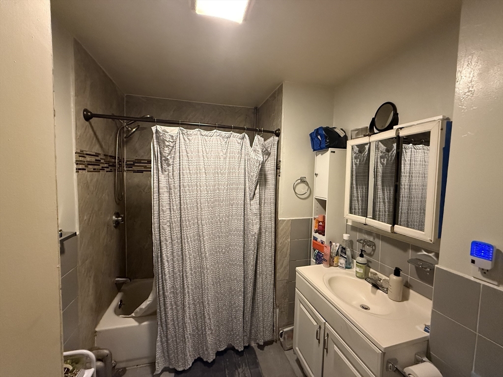 107 Bloomfield Street, Unit 3 Boston, MA 02124 - Photo 10 of 14 a bathroom with a sink vanity granite tub shower and a mirror