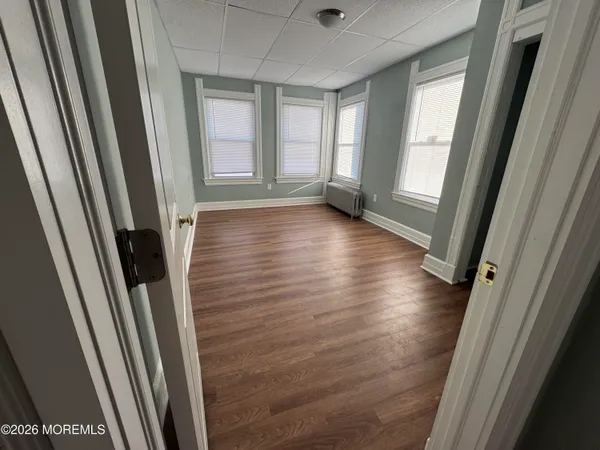 a view of a hallway with wooden floor and windows