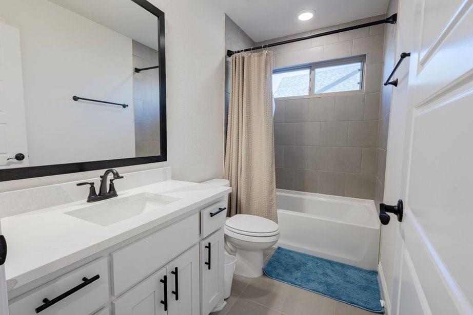14561 Elion Court Pilot Point, TX 76258 - Photo 18 of 36 Bathroom featuring vanity, shower / bath combination with curtain, and light tile patterned floors