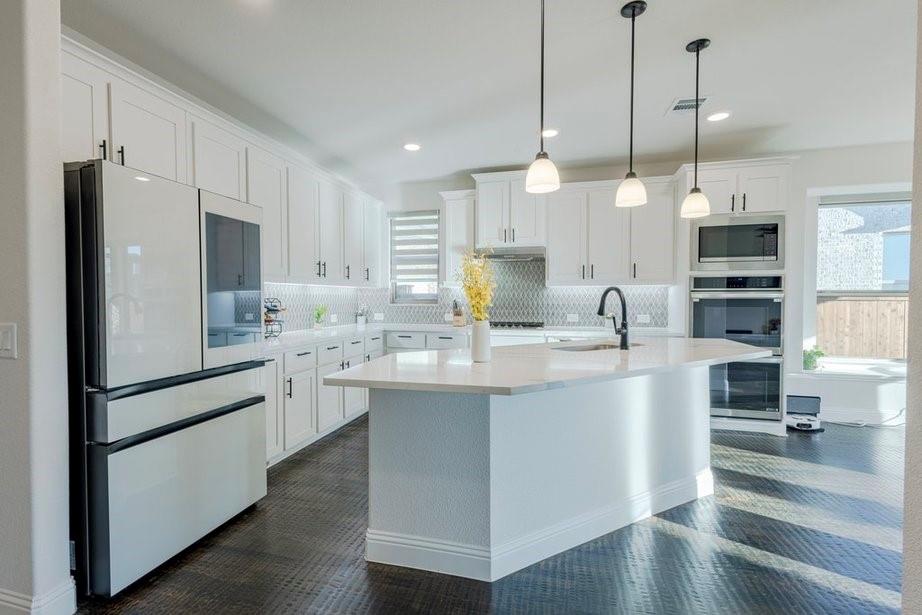 14561 Elion Court Pilot Point, TX 76258 - Photo 27 of 36 Kitchen with stainless steel appliances, white cabinets, decorative backsplash, a center island with sink, and pendant lighting