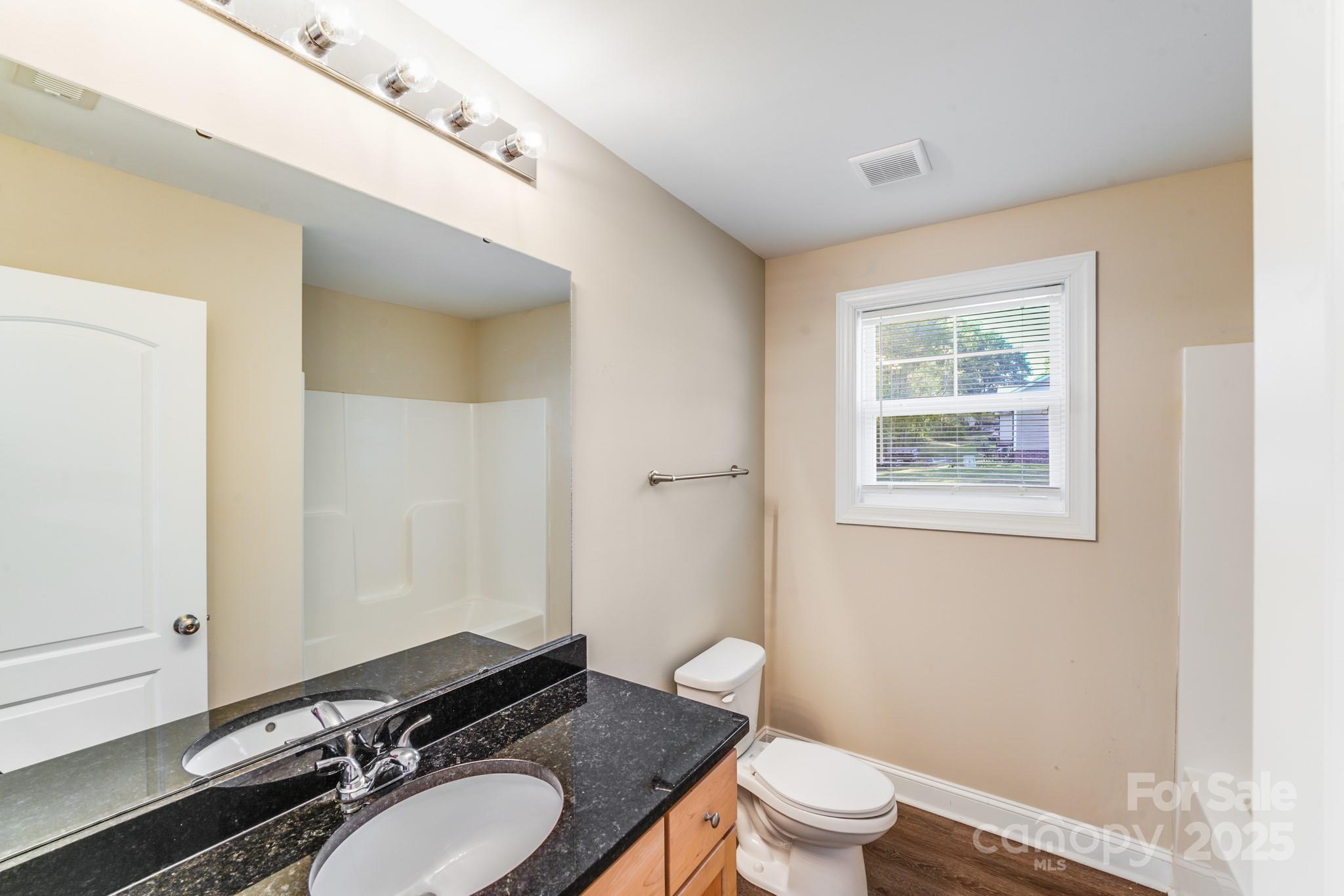 3133 Roberta Road Concord, NC 28027 - Photo 16 of 22 a bathroom with a granite countertop toilet a sink and a mirror