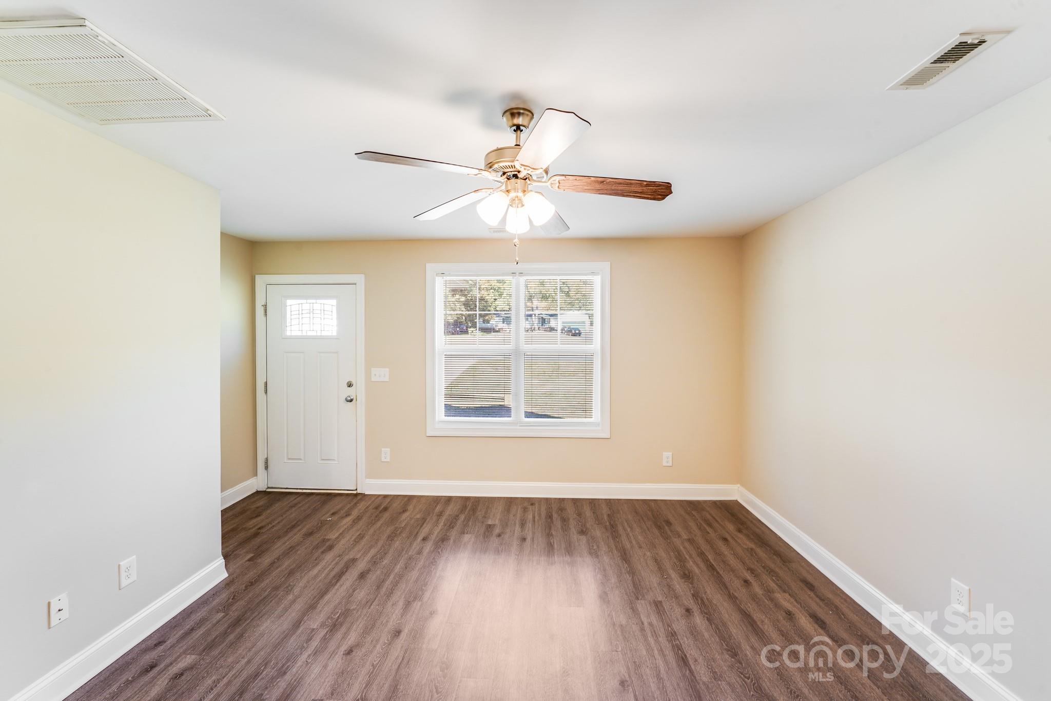 3133 Roberta Road Concord, NC 28027 - Photo 3 of 22 an empty room with wooden floor chandelier fan and windows