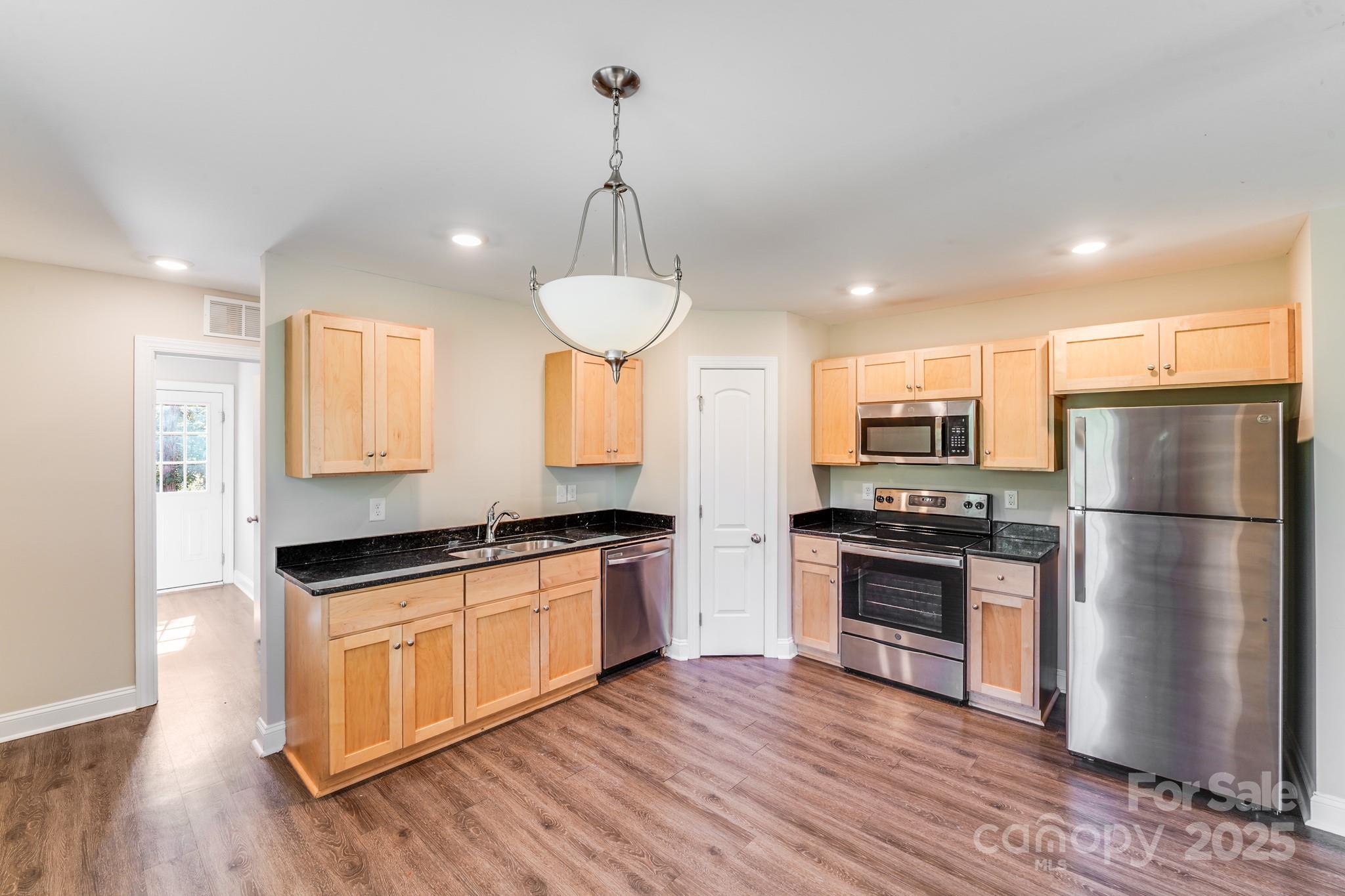 3133 Roberta Road Concord, NC 28027 - Photo 4 of 22 a kitchen with stainless steel appliances a refrigerator a stove a sink cabinets and wooden floor