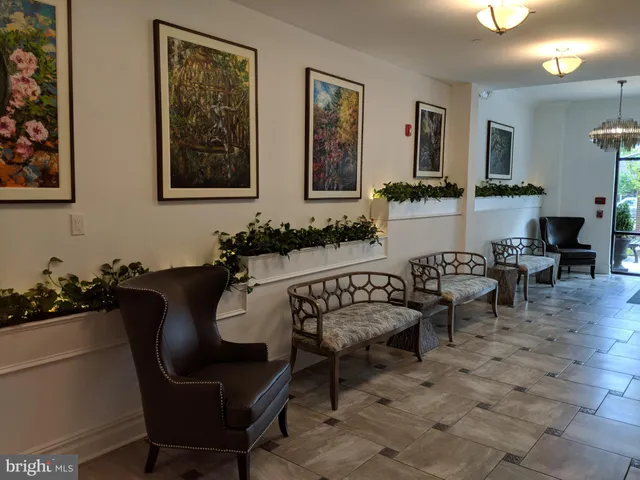a living room with furniture a lamp paintings and a wooden floor