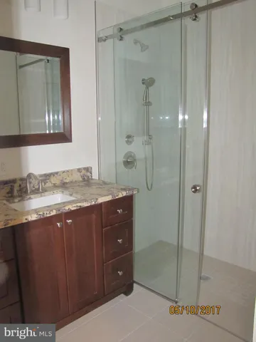 a bathroom with a granite countertop sink a mirror and a shower