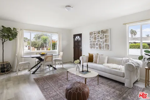 a living room with furniture a table and large windows