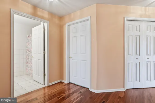 an empty room with wooden floor & closet area