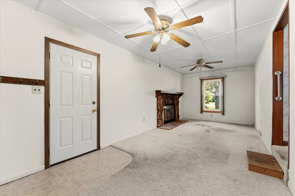 an empty room with chandelier fan and windows