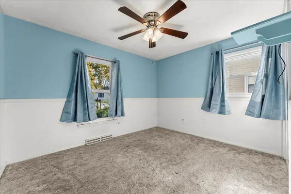 an empty room with windows and fan