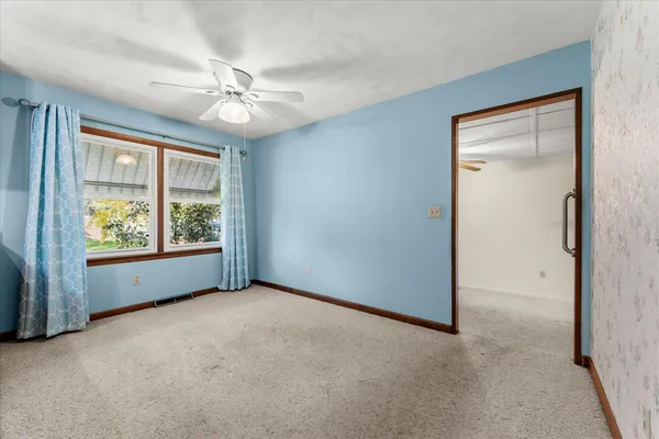 an empty room with windows and fan