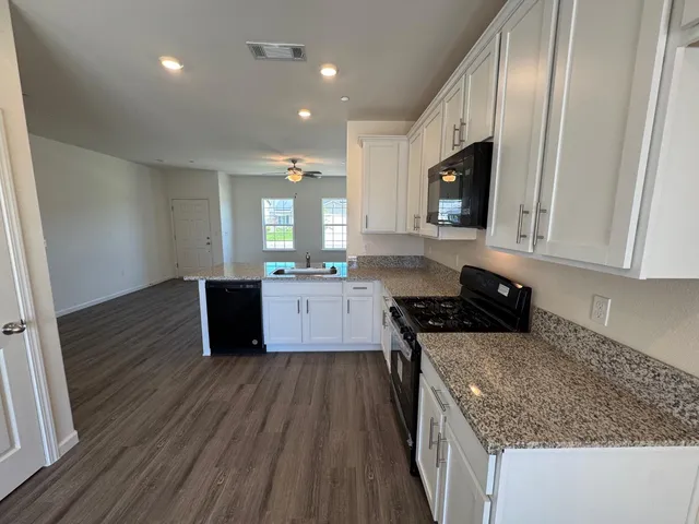 a kitchen with granite countertop a sink stove and cabinets