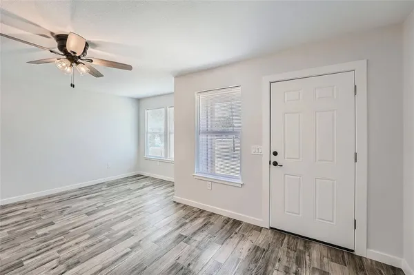 a view of empty room with wooden floor and fan