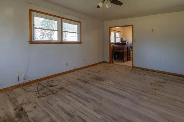 an empty room with wooden floor cabinet and windows