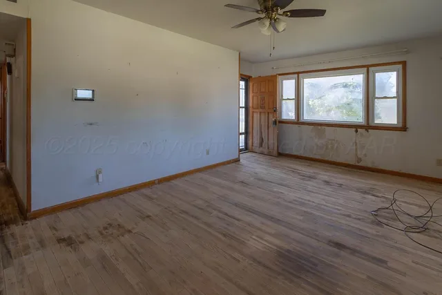 a view of an empty room with a window and wooden floor