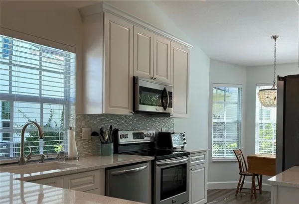 a kitchen with stainless steel appliances granite countertop a refrigerator a stove a sink dishwasher and white cabinets with wooden floor