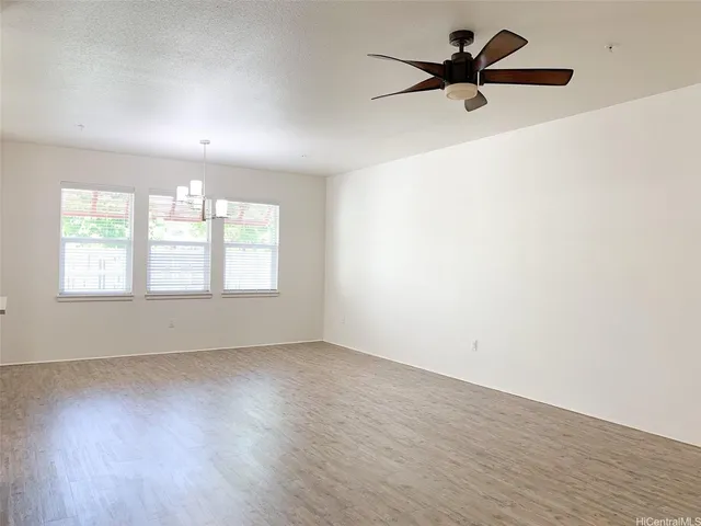 an empty room with wooden floor fan and windows