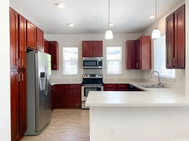 a kitchen with stainless steel appliances granite countertop a refrigerator a stove and a sink with wooden floor