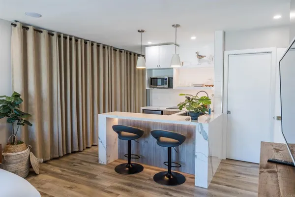 a kitchen with stainless steel appliances a sink a counter top space a large window and wooden floor