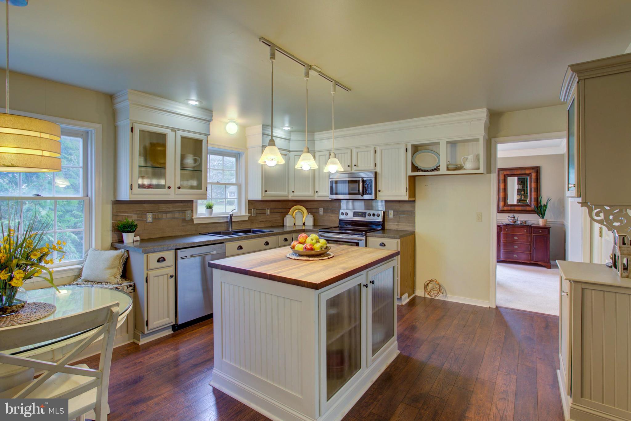 239 Kingsbridge Drive Lititz, PA 17543 - Photo 11 of 37 a kitchen with kitchen island a stove a refrigerator and a dining table with wooden floor