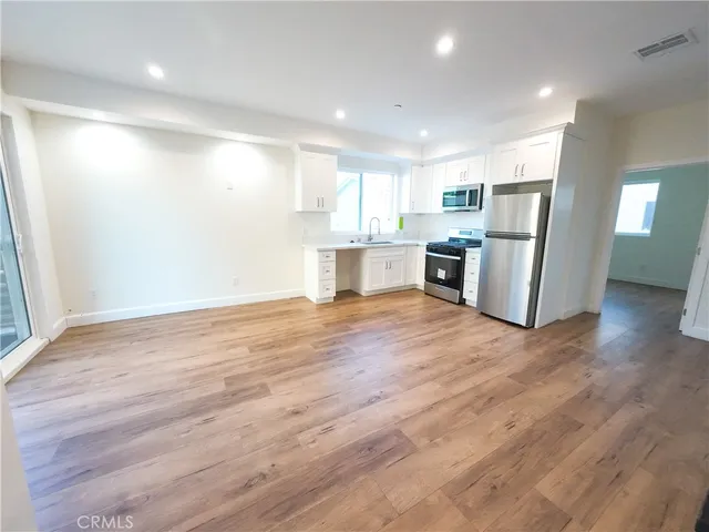 a view of kitchen with kitchen island wooden floor center island and stainless steel appliances