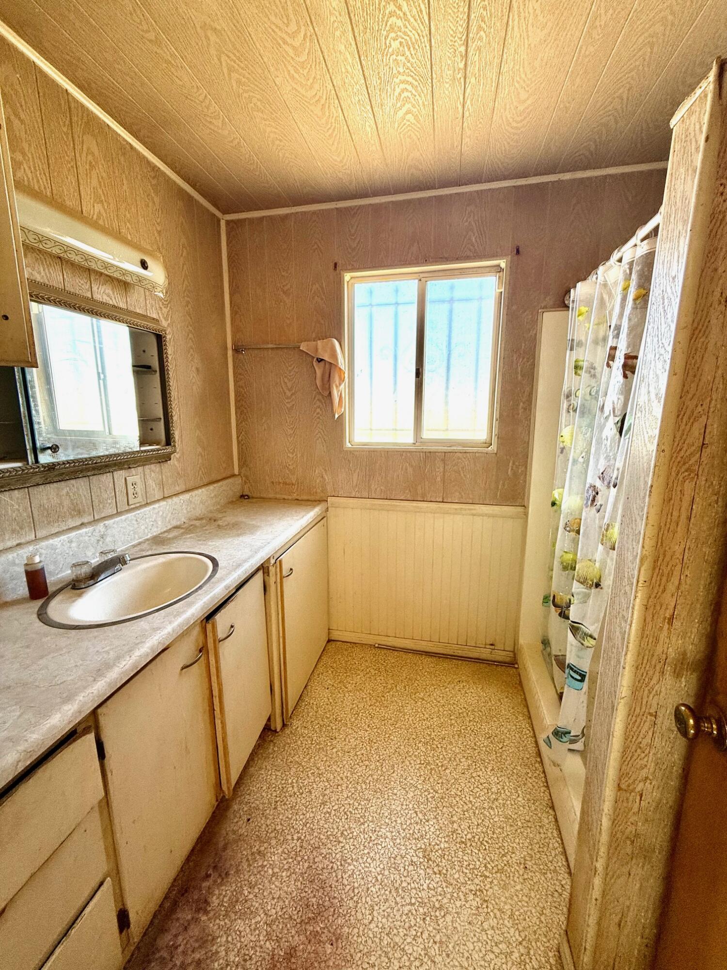 7990 Ramas Avenue Yucca Valley, CA 92284 - Photo 9 of 19 a bathroom with a granite countertop sink a mirror a vanity and a shower