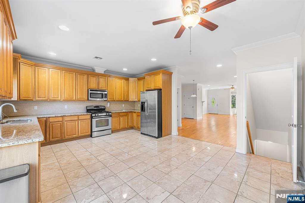 233 5th Street, Unit B Fairview, NJ 07022 - Photo 10 of 31 a large kitchen with stainless steel appliances kitchen island granite countertop a refrigerator oven a sink a dining table and chairs with wooden floor